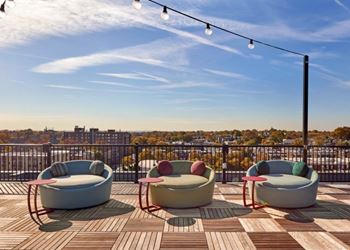 Three round cushioned seating areas on a wooden deck with a cityscape in the background.